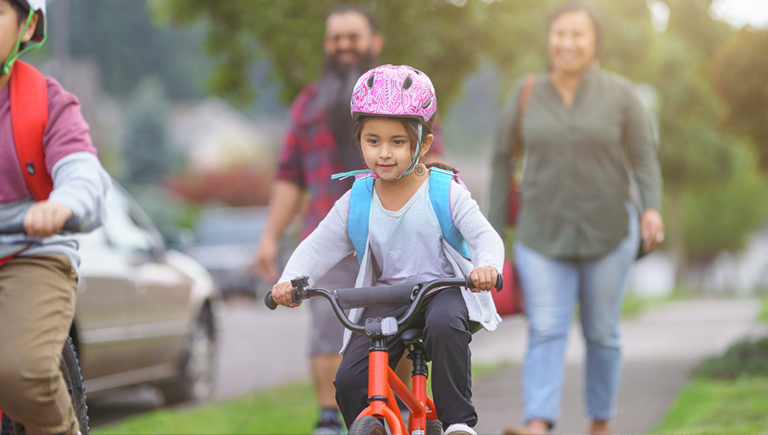 Two kids on bikes with two adults following behind them