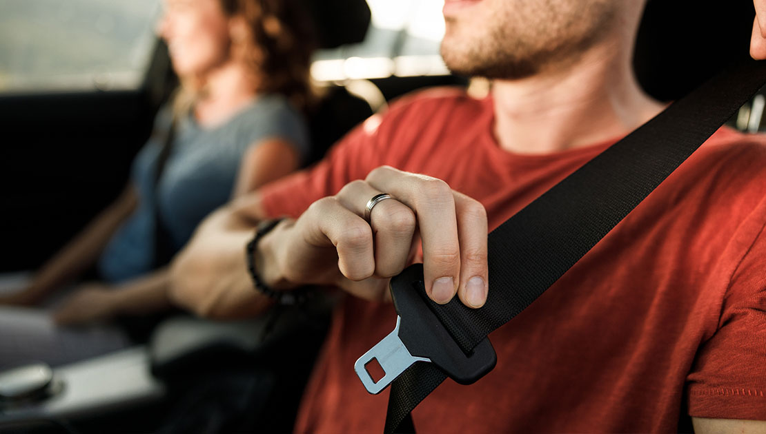 Man pulling the seat belt down to buckle up in his car