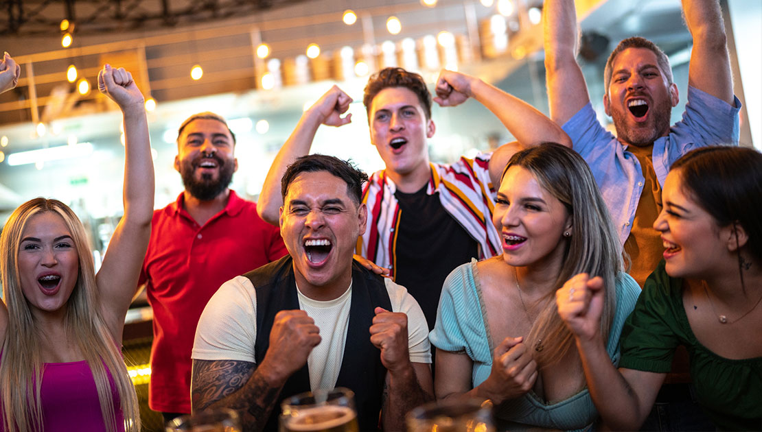 group of friends cheering at a bar during a football game