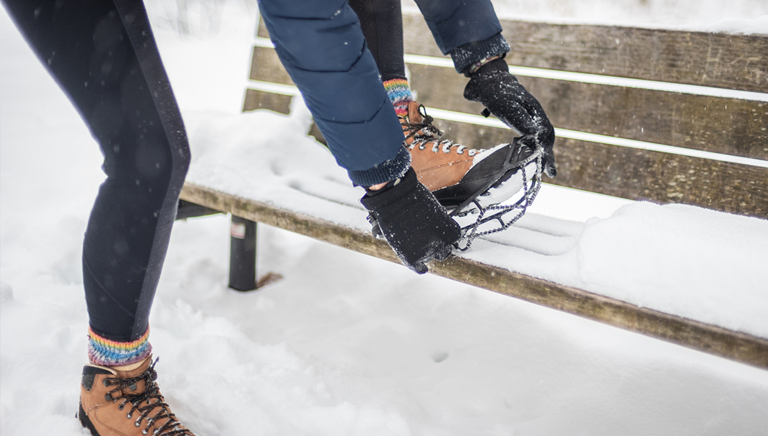 close up of person putting on ice cleats on her walking shoes