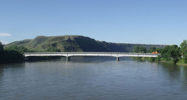 Image of a steel girder bridge in Fort Benton, MT, with a scenic view of the Missouri River Breaks