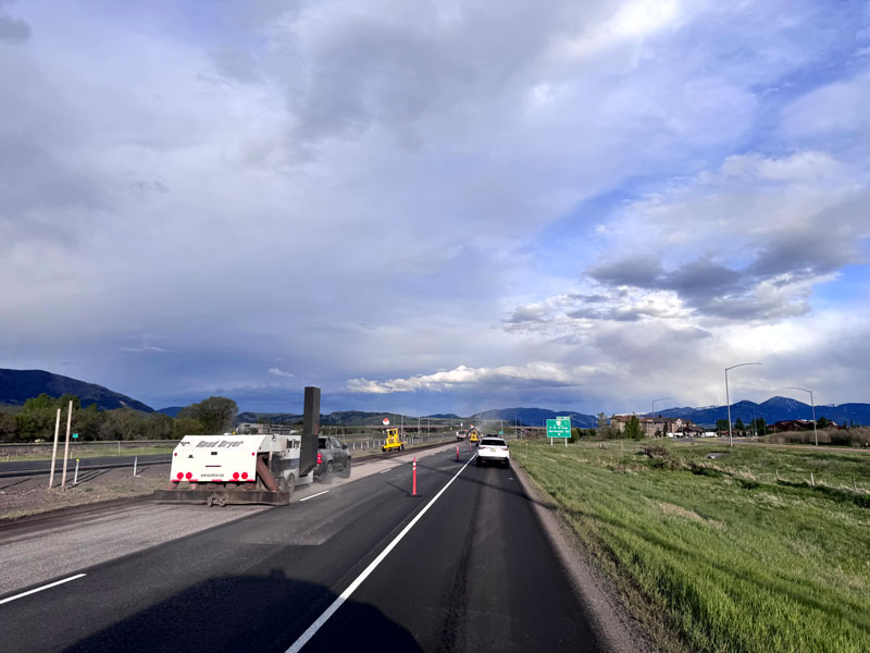 road under construction with mountains and clouds in the distance