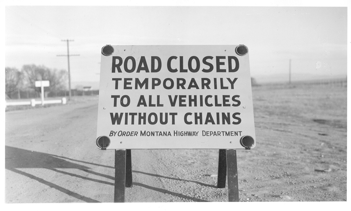 historical road sign that reads Road Closed Temporarily to all vehicles without chains, by order Montana Highway Department
